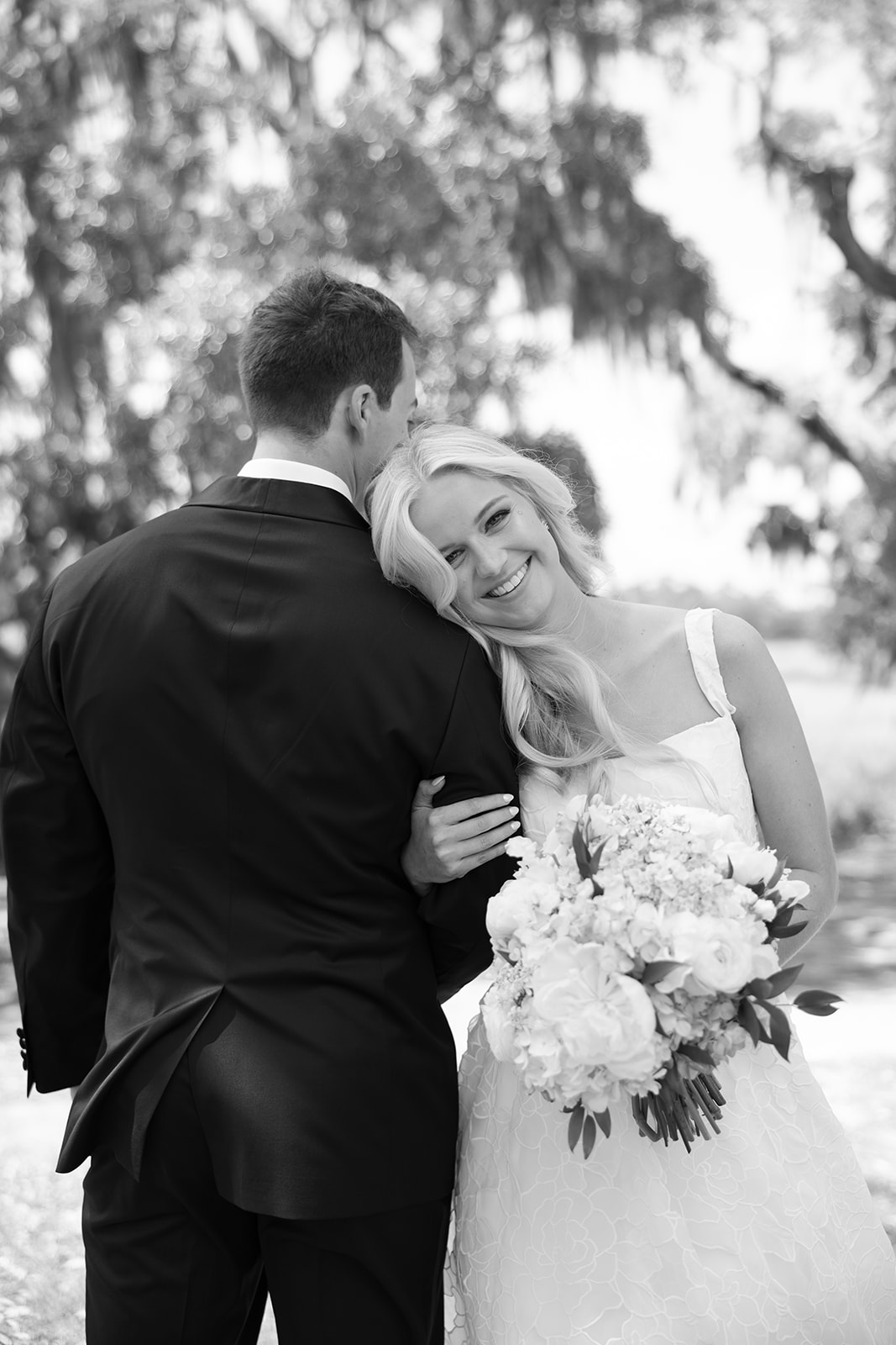 Bride smiles at the camera as she leans on the shoulder of her groom at Boone Hall Plantation wedding