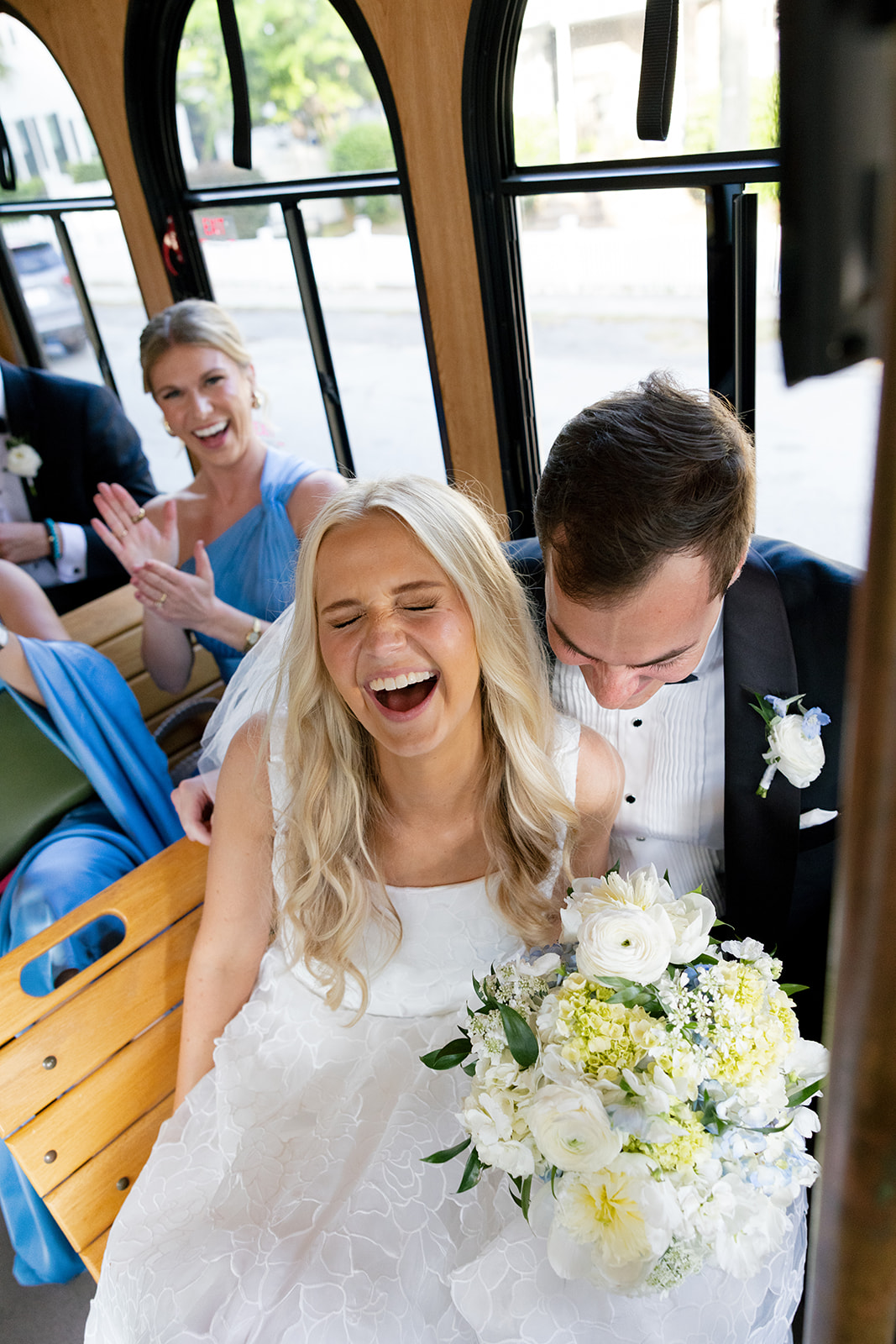 bride and groom laugh with their bridal party on the trolley ride to their wedding reception at Boone Hall Plantation