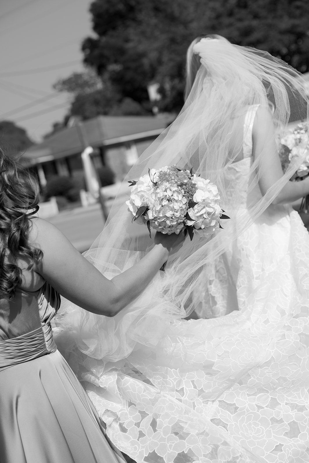 bridesmaid helping bride walk to Boone Hall Plantation
