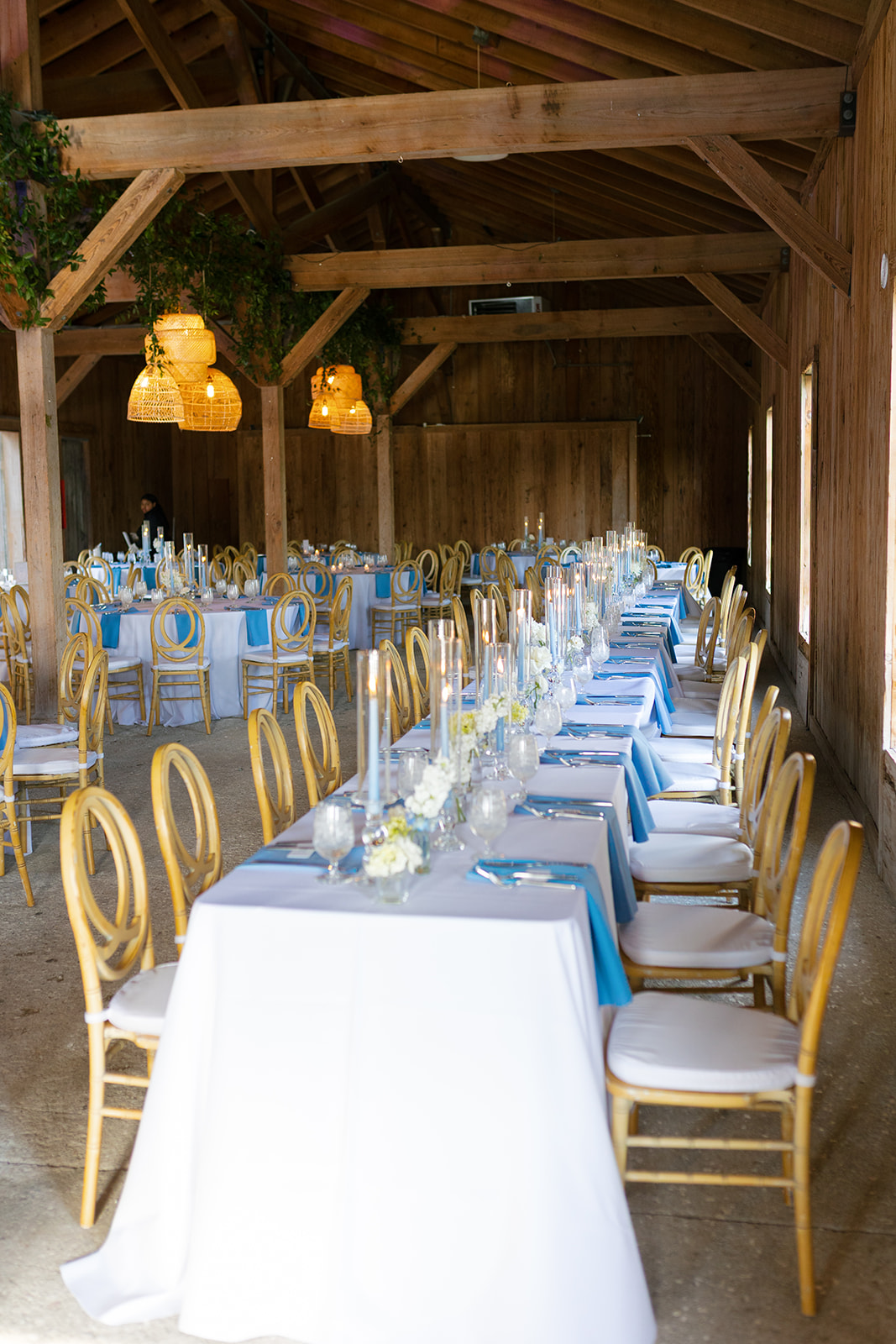 Long reception tables with blue and white details inside the Cotton Dock at Boone Hall Plantation wedding venue in Charleston, SC.