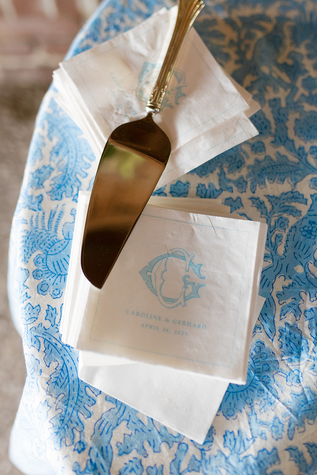 Custom monogrammed wedding napkins and cake server on blue floral linen at Boone Hall Plantation wedding reception.