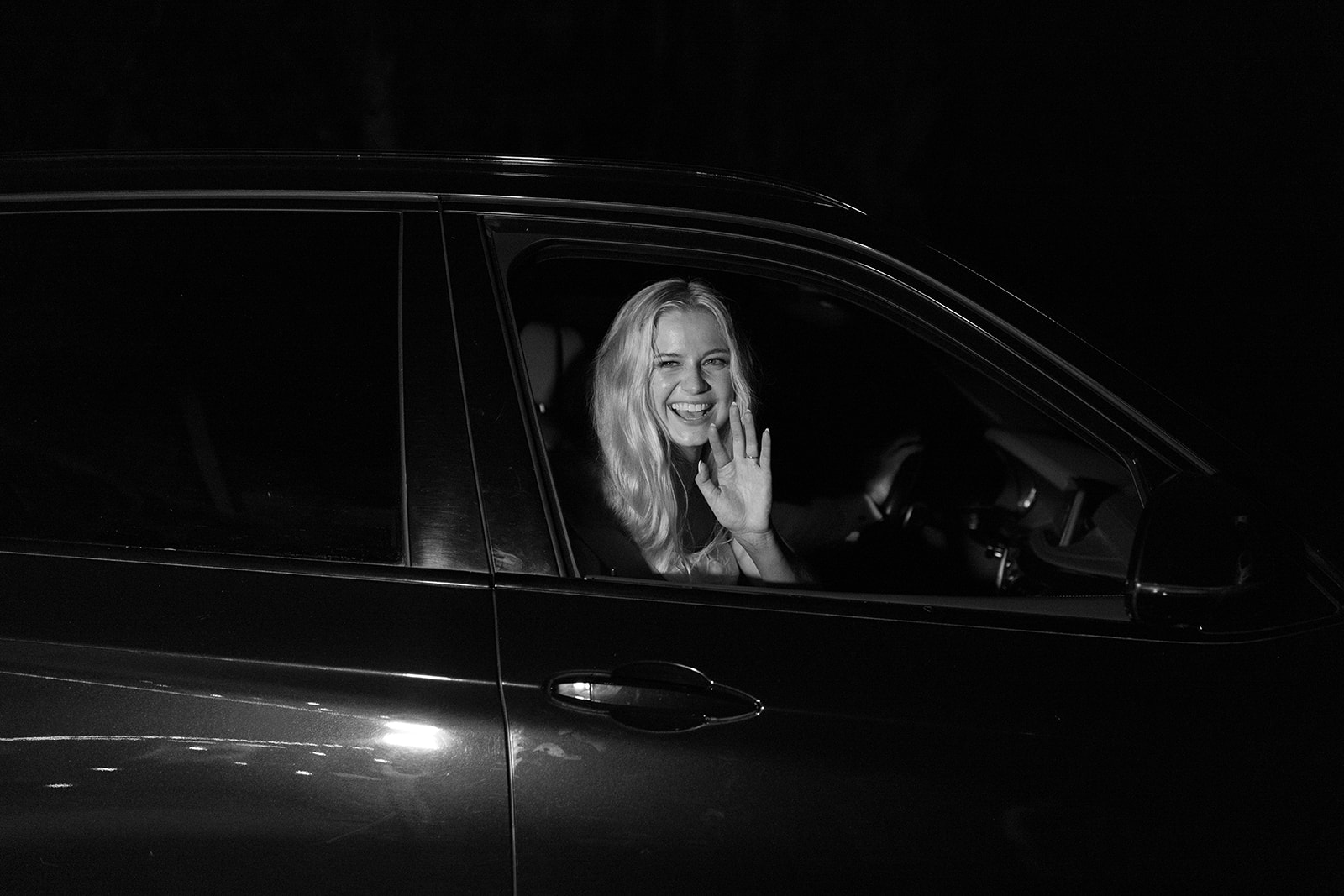 bride waves goodbye as she leaves the wedding