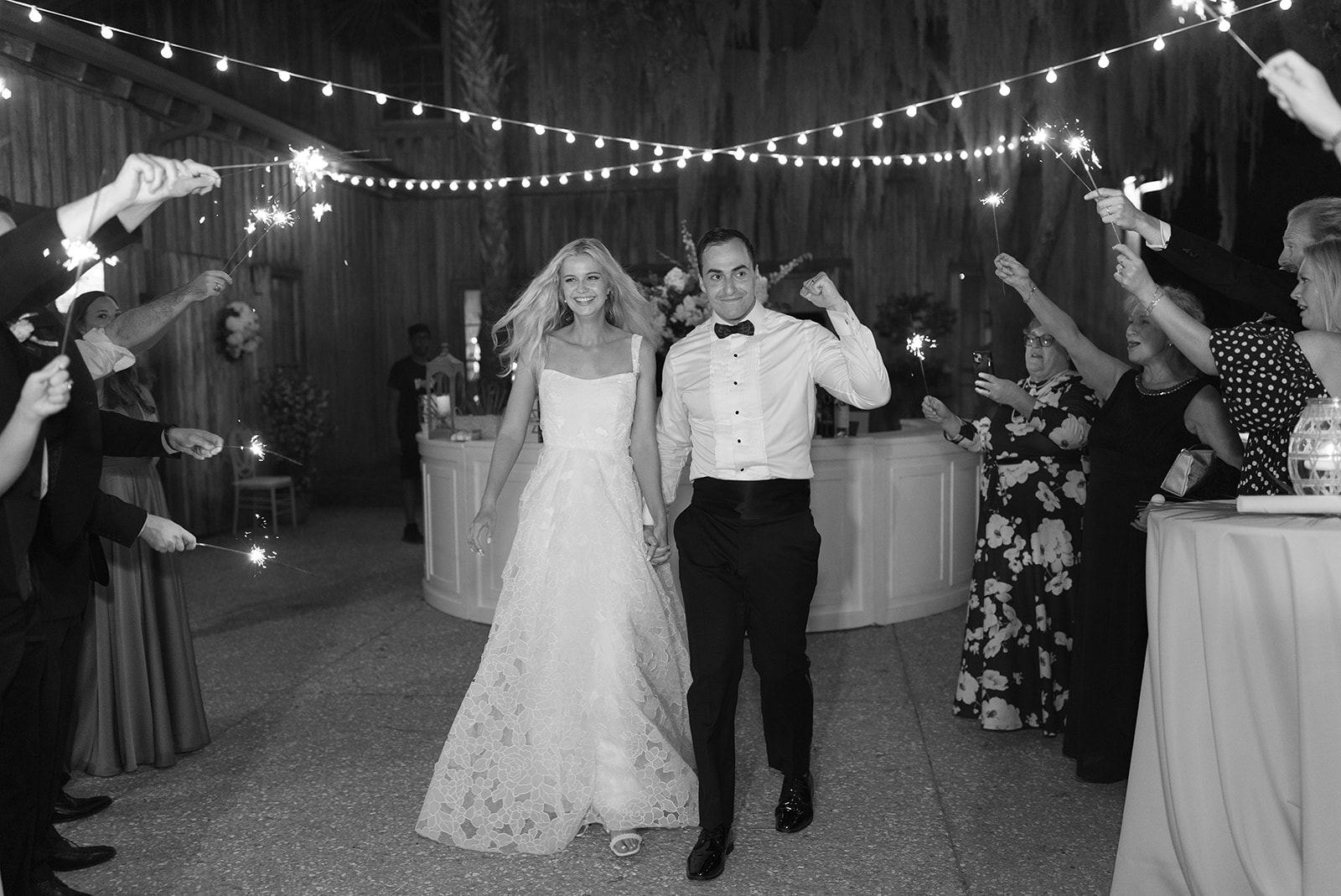 bride and groom walk through the guest tunnel with sparklers at their wedding sendoff