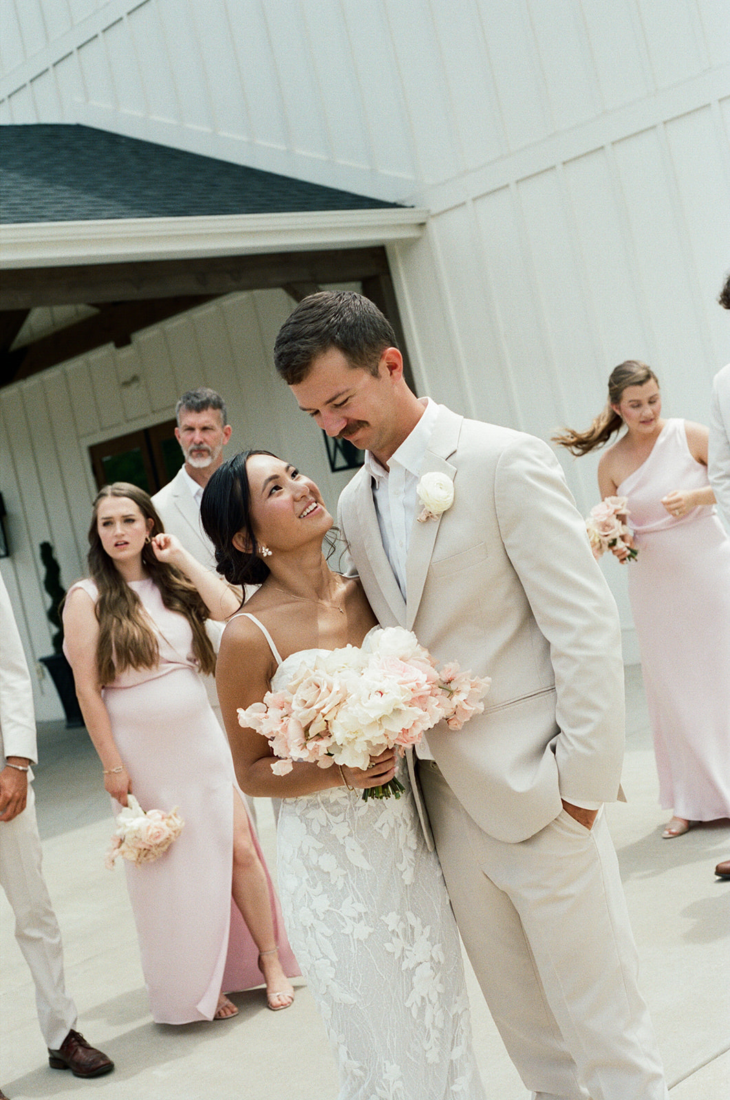 film photo of birde and groom smiling as their bridal party watches