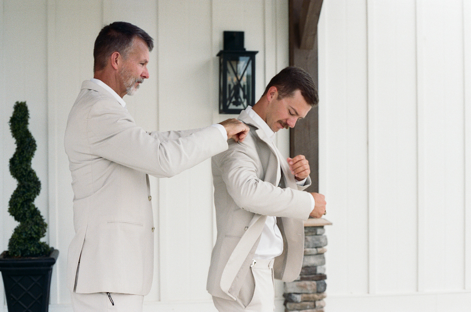 film photo of the father of the groom helping him put on his suit jacket