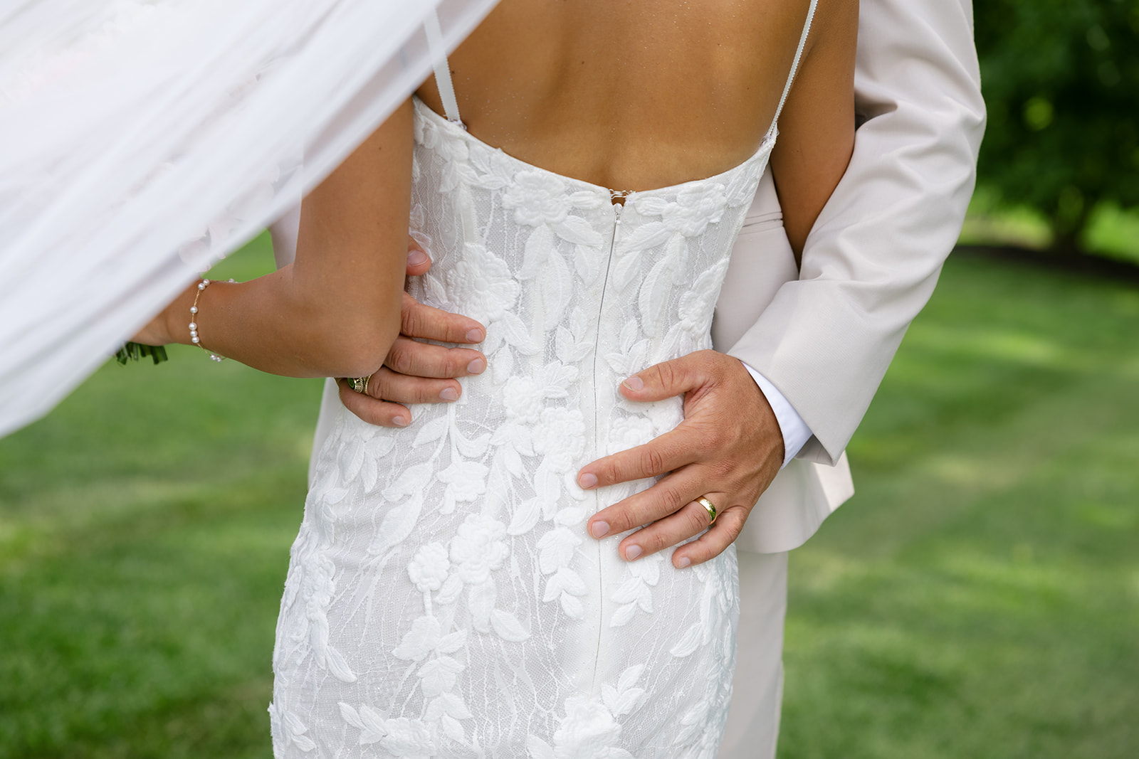 close-up detail shot of the bride's wedding dress as the groom holds her waist