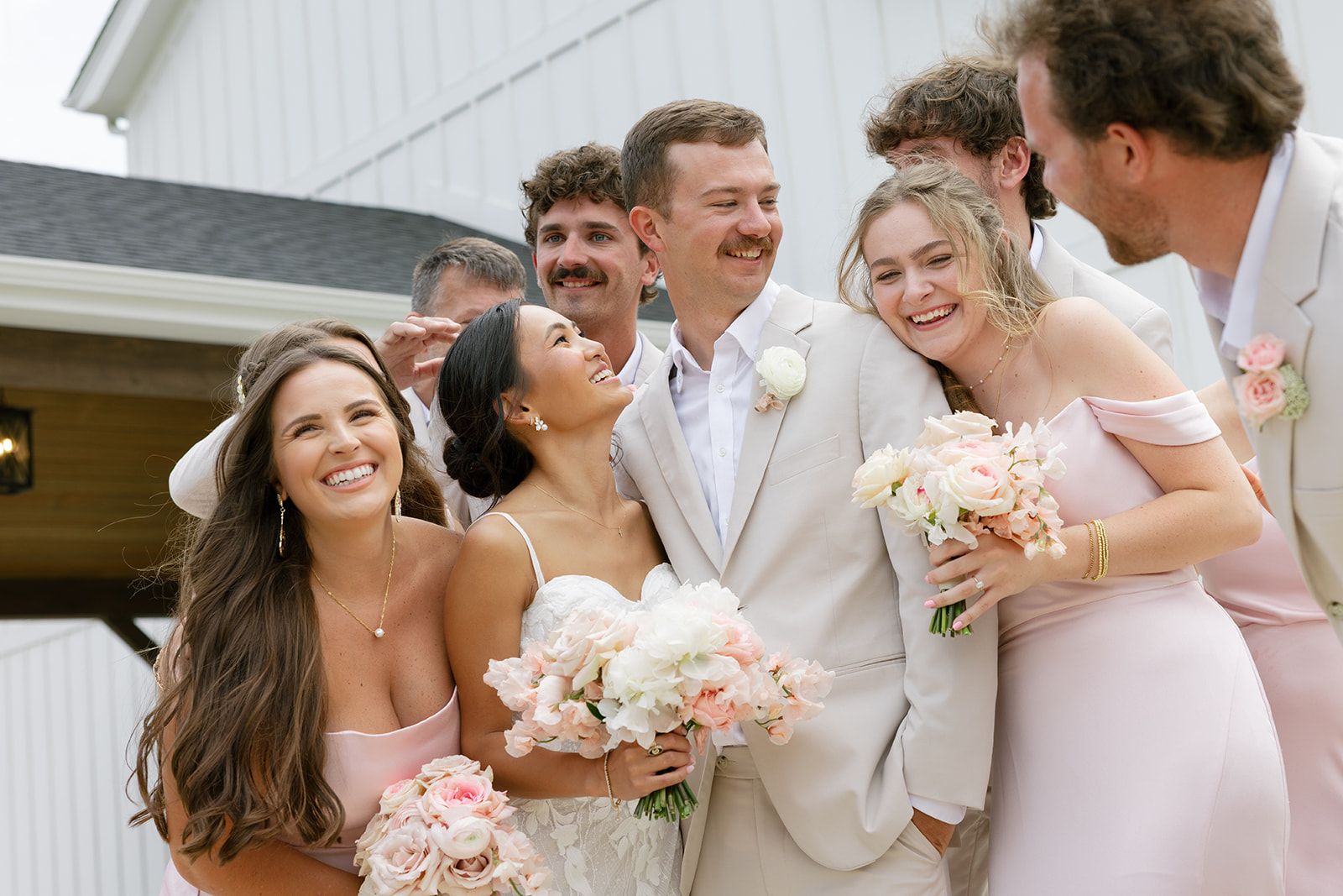 bridesmaids and groomsmen laugh with the newlyweds outside their South Carolina wedding venue