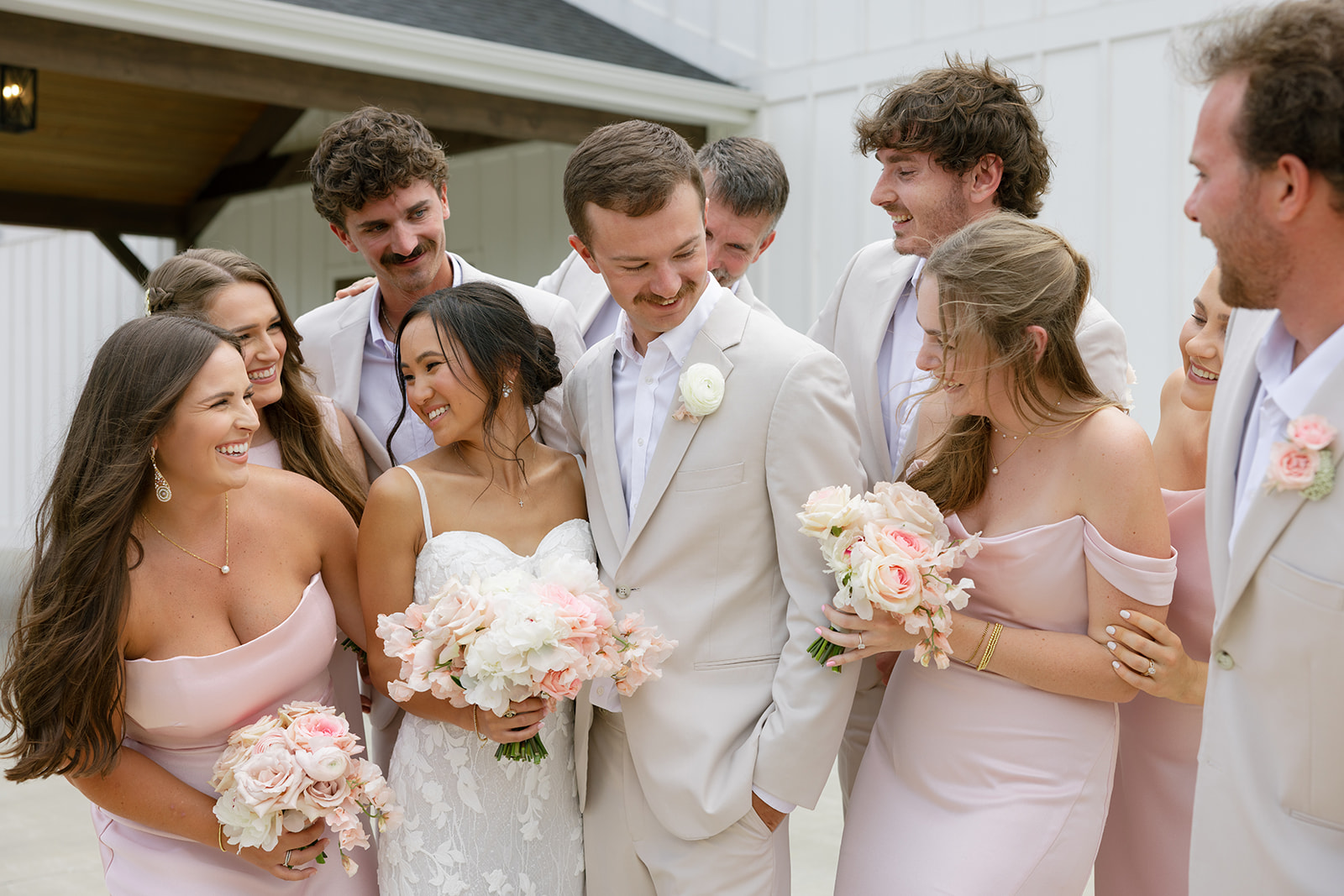 bridesmaids and groomsmen smile at the newlyweds outside their South Carolina wedding venue