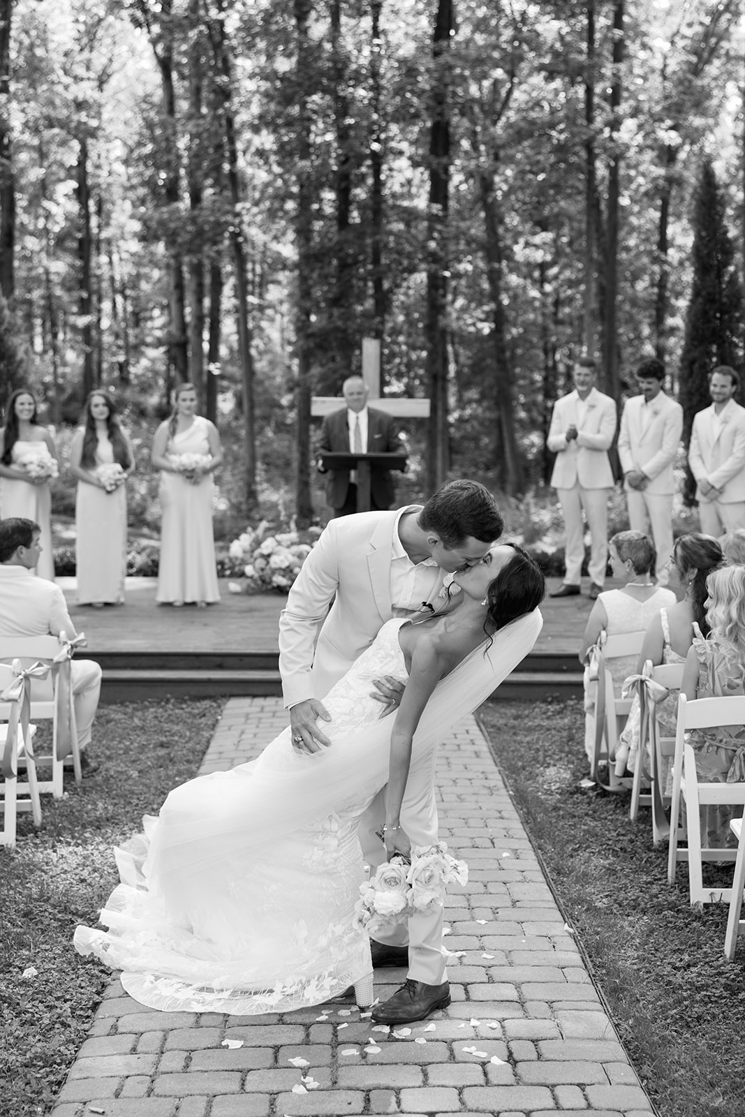 groom dips bride for a kiss as they walk down the aisle