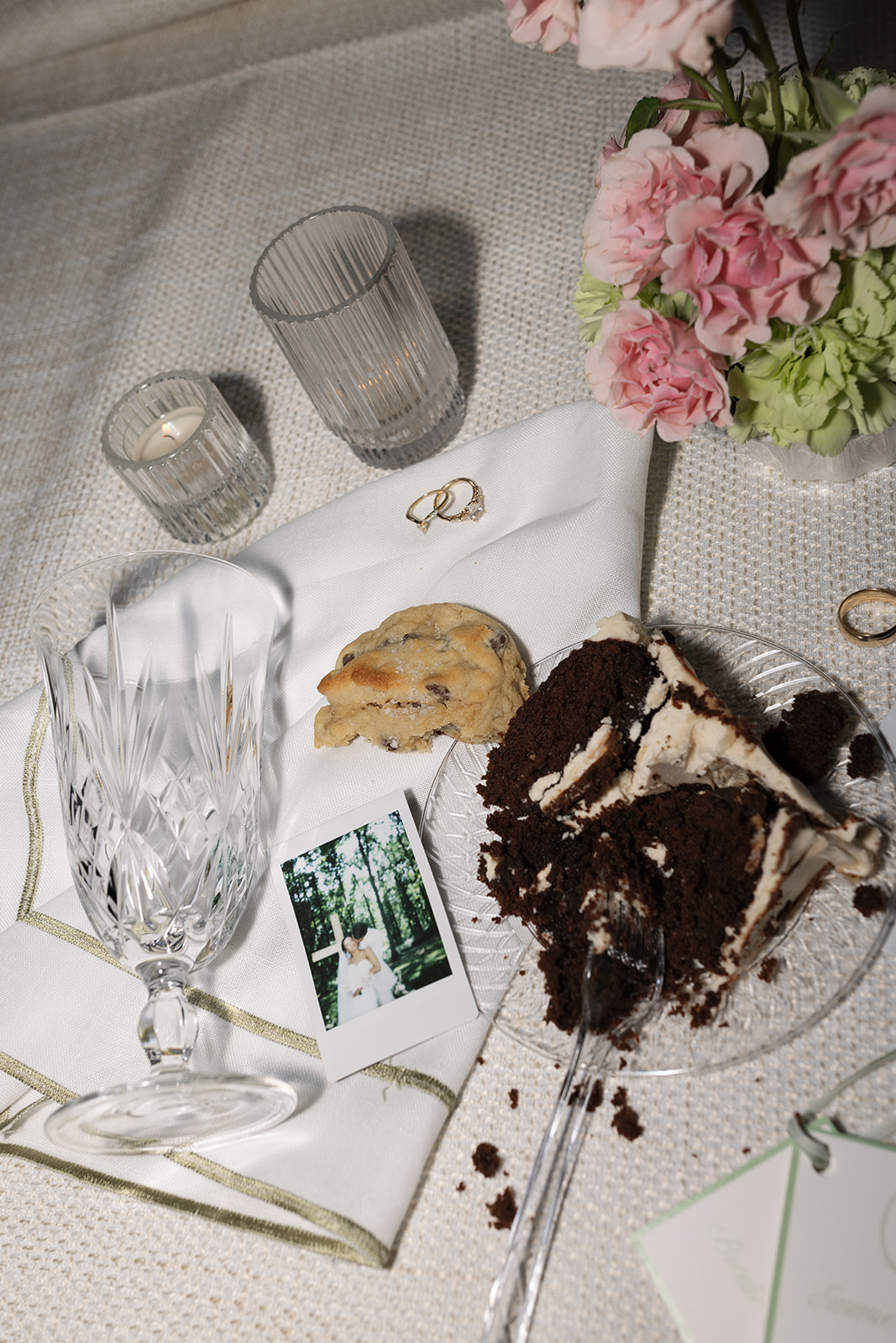 late-night flat lay shot of wedding cake, a cookie, and a floral centerpiece at a wedding reception 