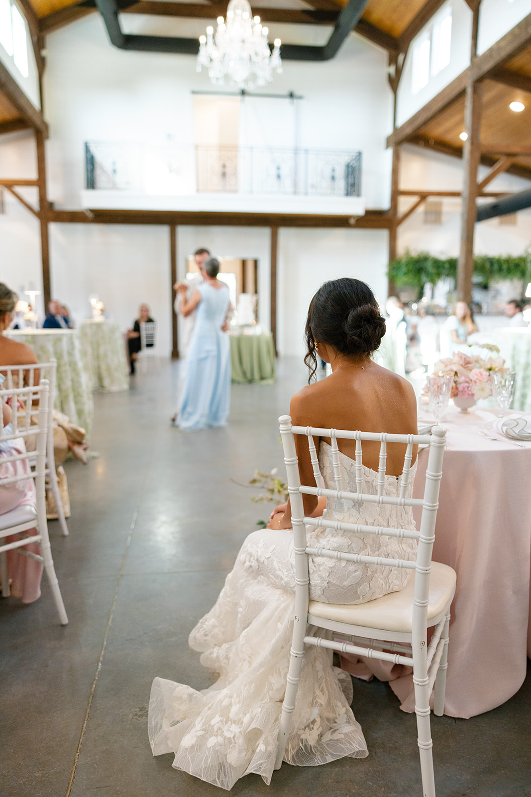 stunning shot of the bride watching her new husband share a dance with his mother at their wedding reception