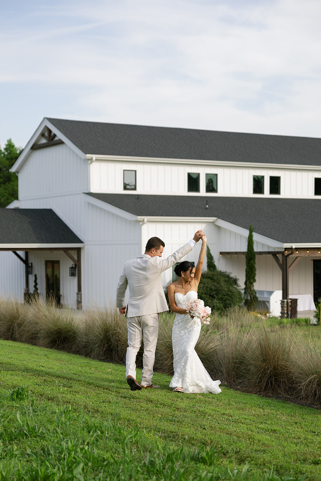 Groom twirls his new wife in the field outside The Venue at Edgewood