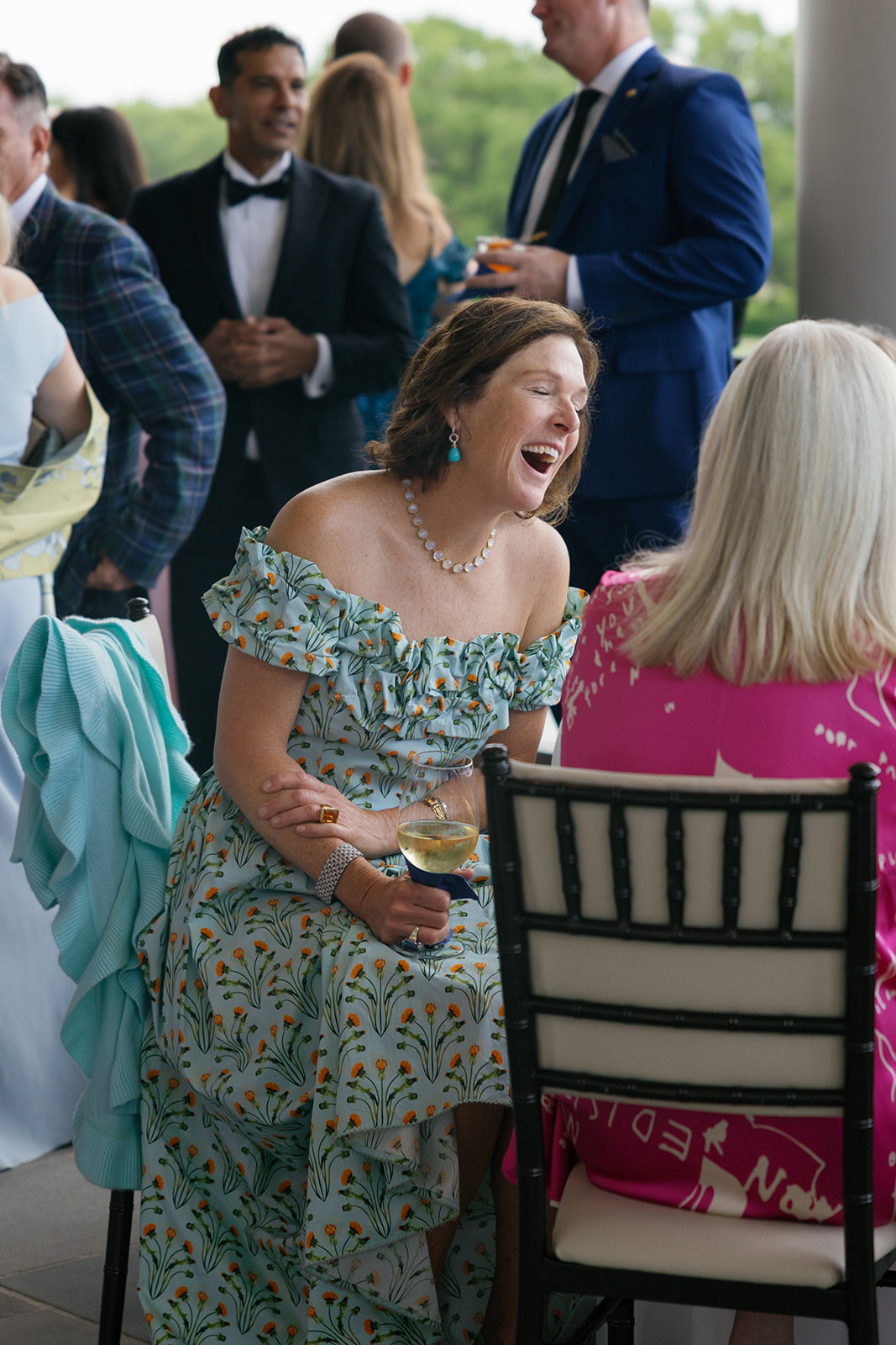 wedding guest laughing and chatting at cocktail hour, captured as part of the wedding photography package