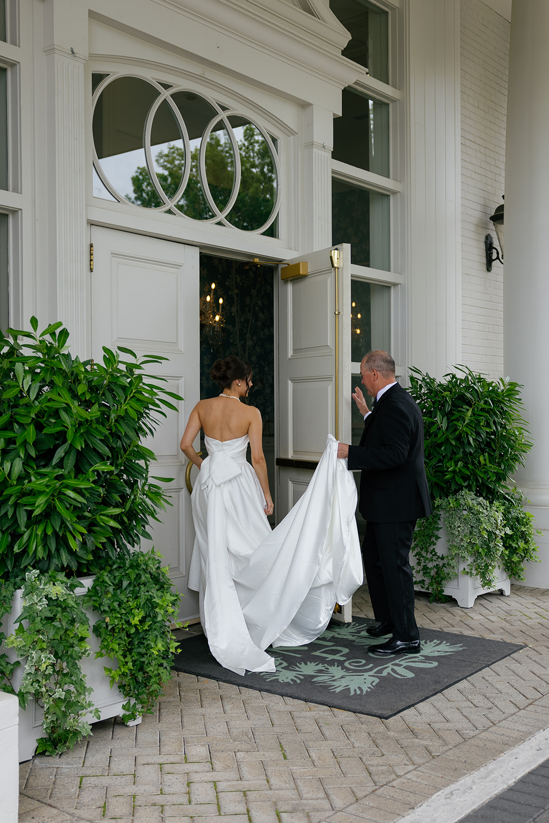 The father of the bride holds the door open for the bride