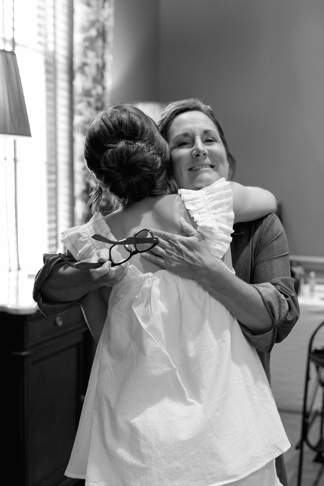 Black and white photo of the bride sharing an emotional hug with a family member while getting ready at Myers Park Country Club.