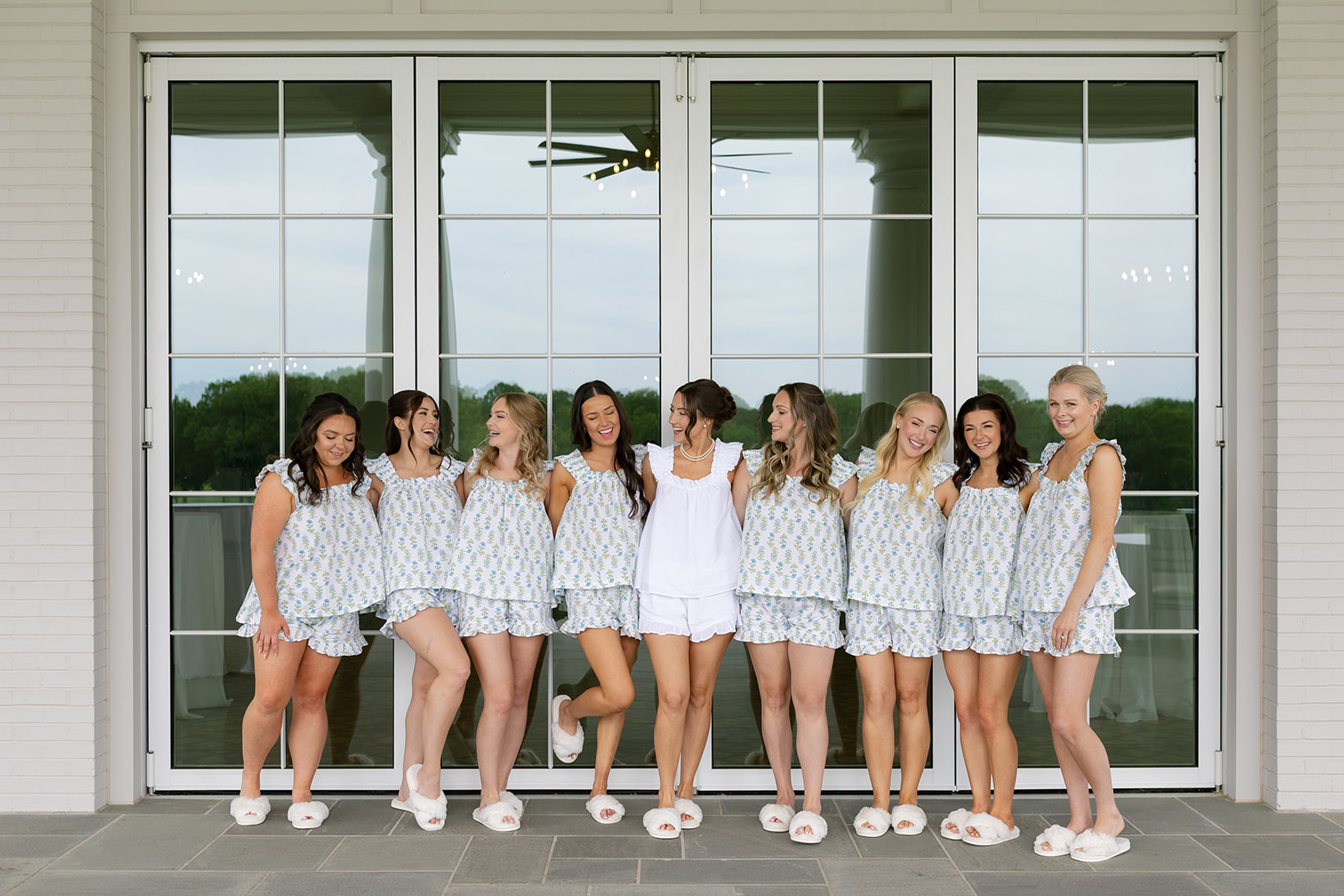Joyful photo of the bride and bridesmaids sharing a laugh in matching getting ready outfits at Myers Park Country Club.