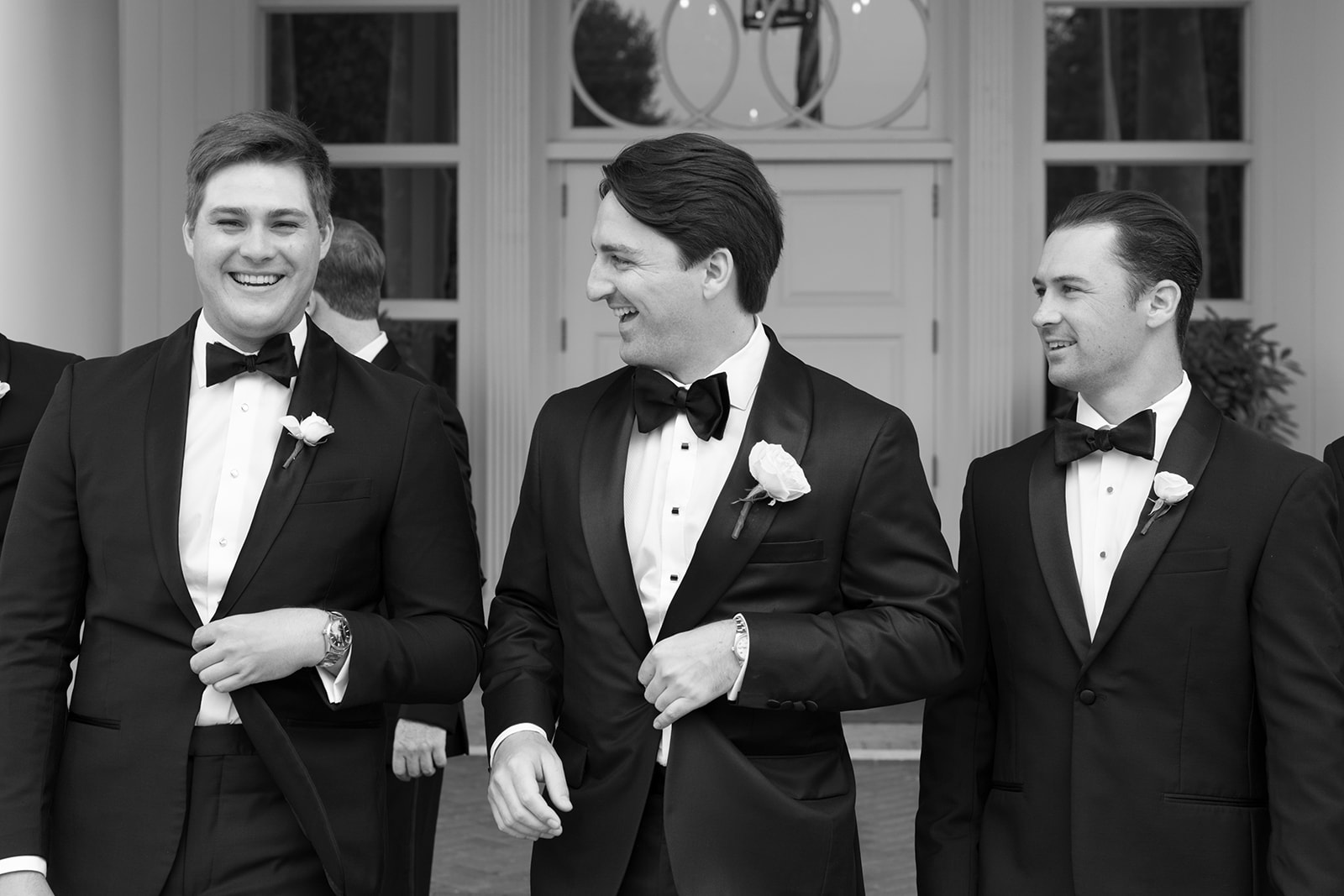 Close-up black-and-white photo of groom laughing with groomsmen.