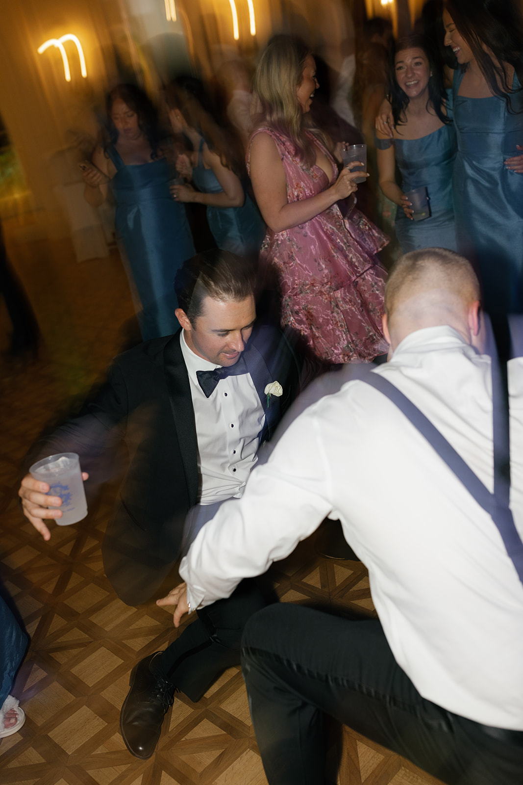 Guests smiling and holding drinks on the dance floor with a fun party atmosphere.