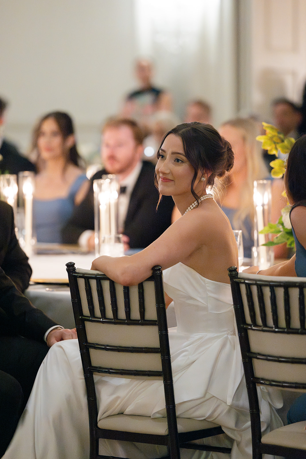 Bride smiles while listening to a toast during the wedding reception.