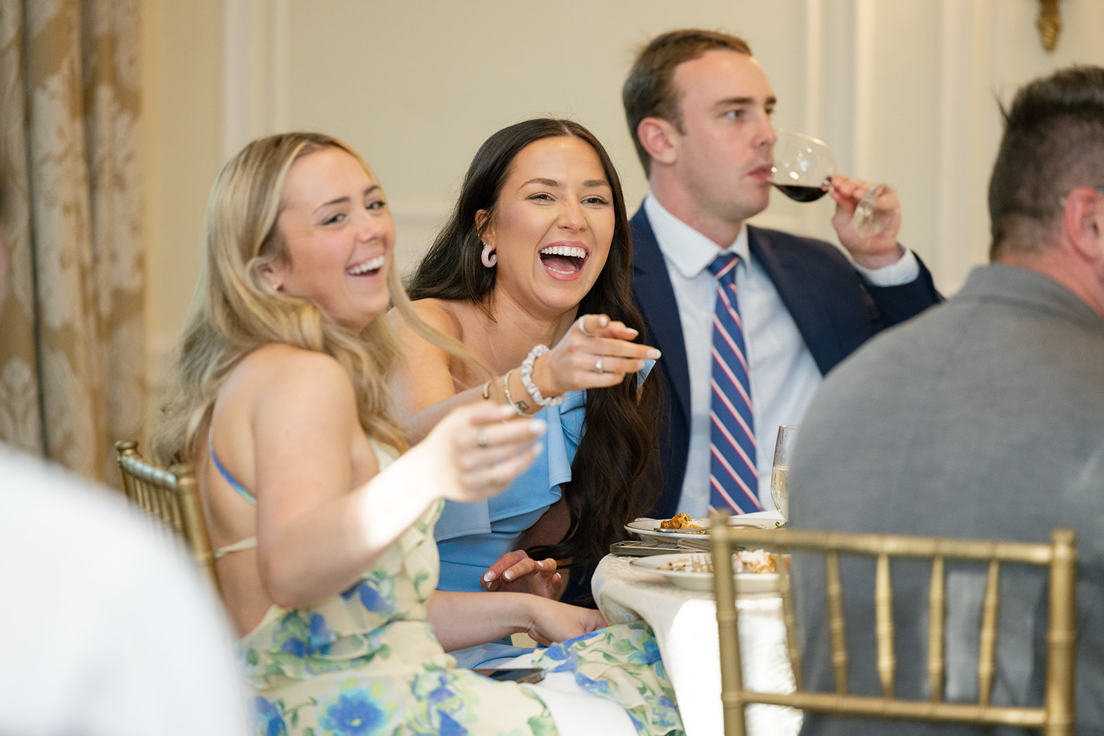 Friends laughing and celebrating at the rehearsal dinner inside Duke Mansion, captured as part of the wedding photography package.