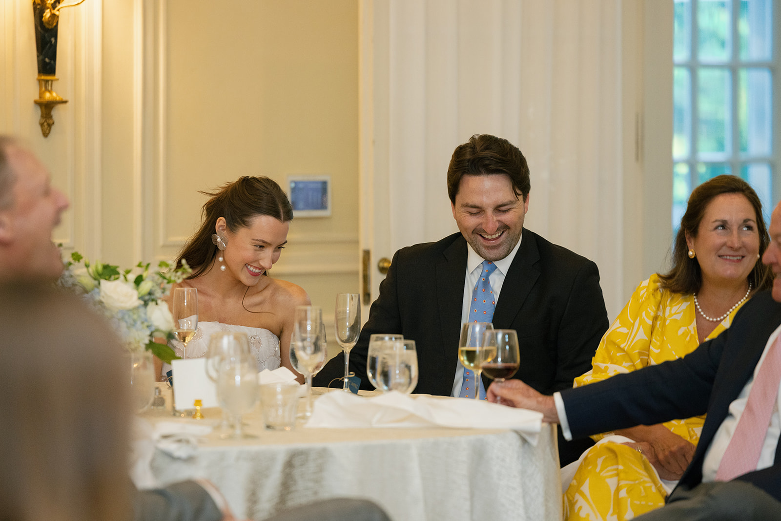 bride and groom laughing and celebrating at the rehearsal dinner inside Duke Mansion, captured as part of the wedding photography package.