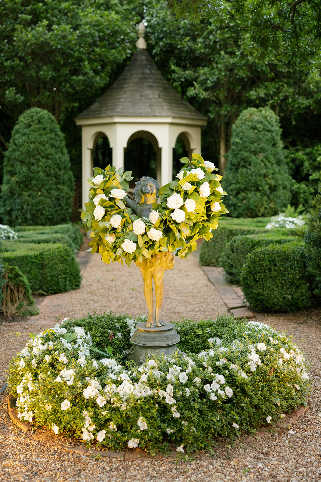Romantic garden statue with floral wreath at a North Carolina welcome party, captured as part of a wedding photography package.
