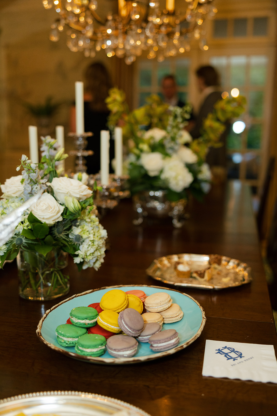 Colorful macarons served on an elegant dining table with white rose centerpieces during a North Carolina wedding welcome party