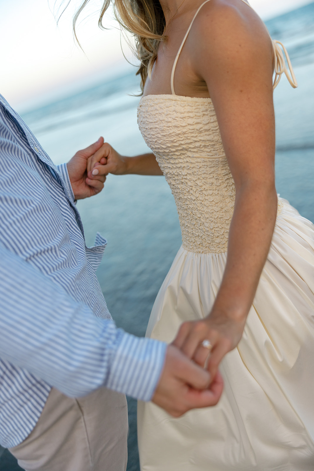 Close-up of the couple holding hands during their Charleston SC engagement session, showing off the bride-to-be’s engagement ring against the ocean backdrop.