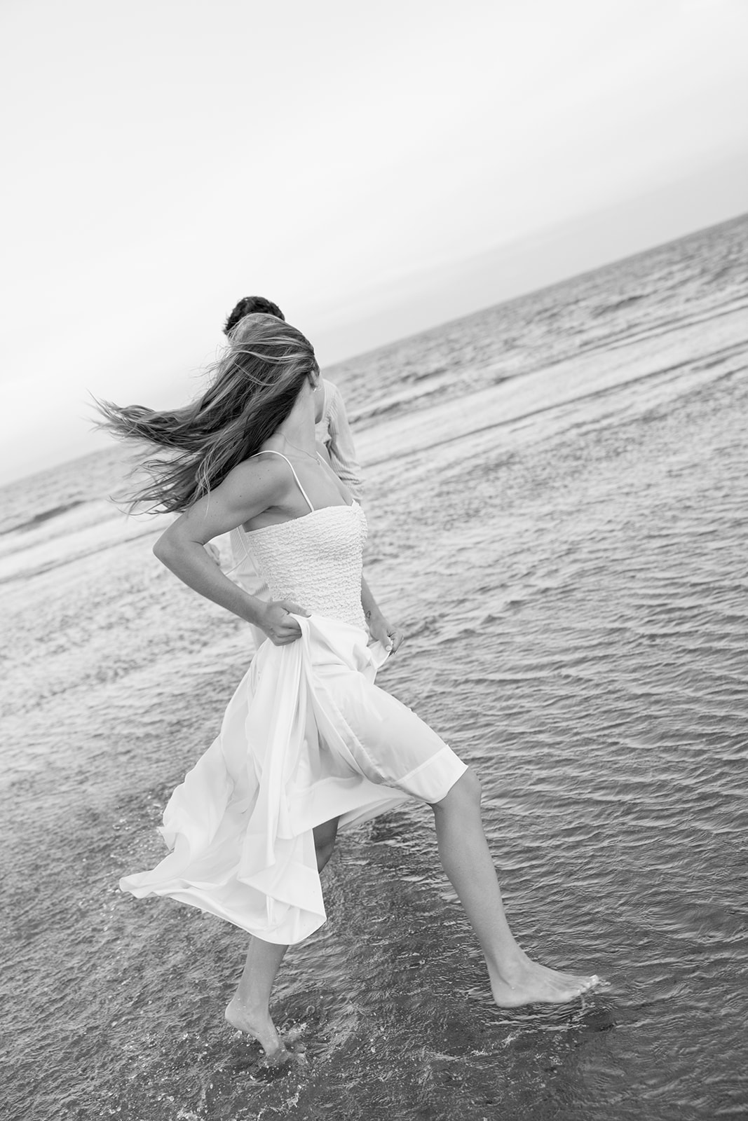 Playful moment of couple running through the waves together