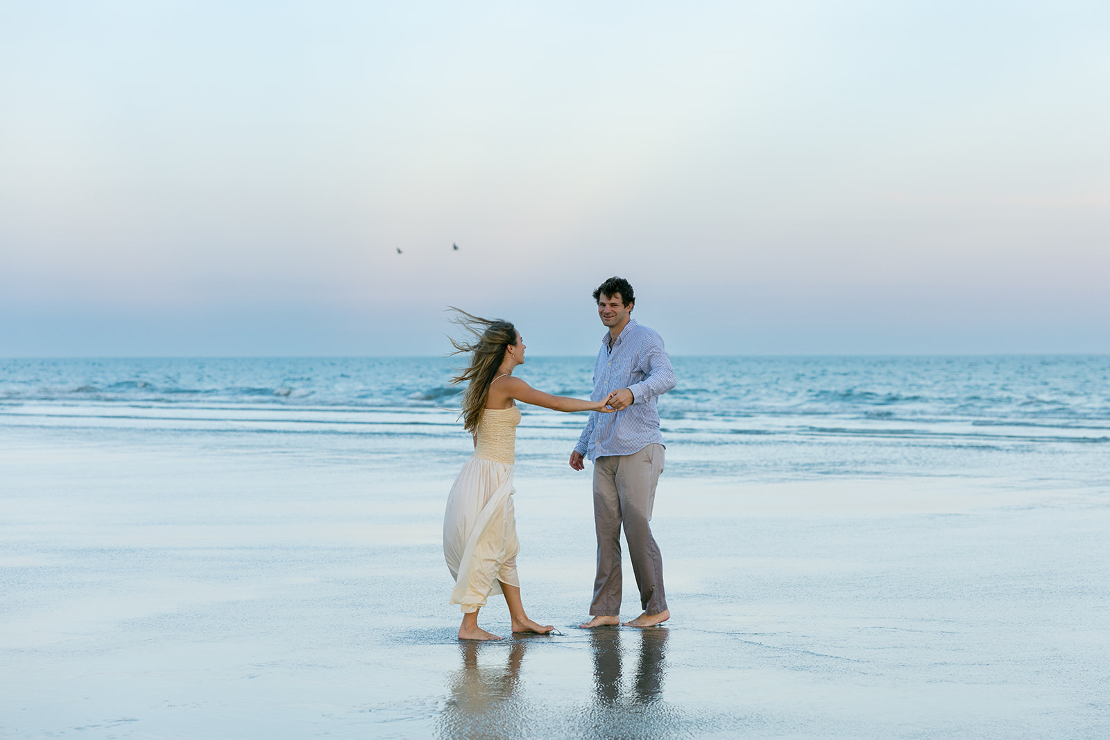 Couple walking barefoot along the beach during Charleston engagement photos