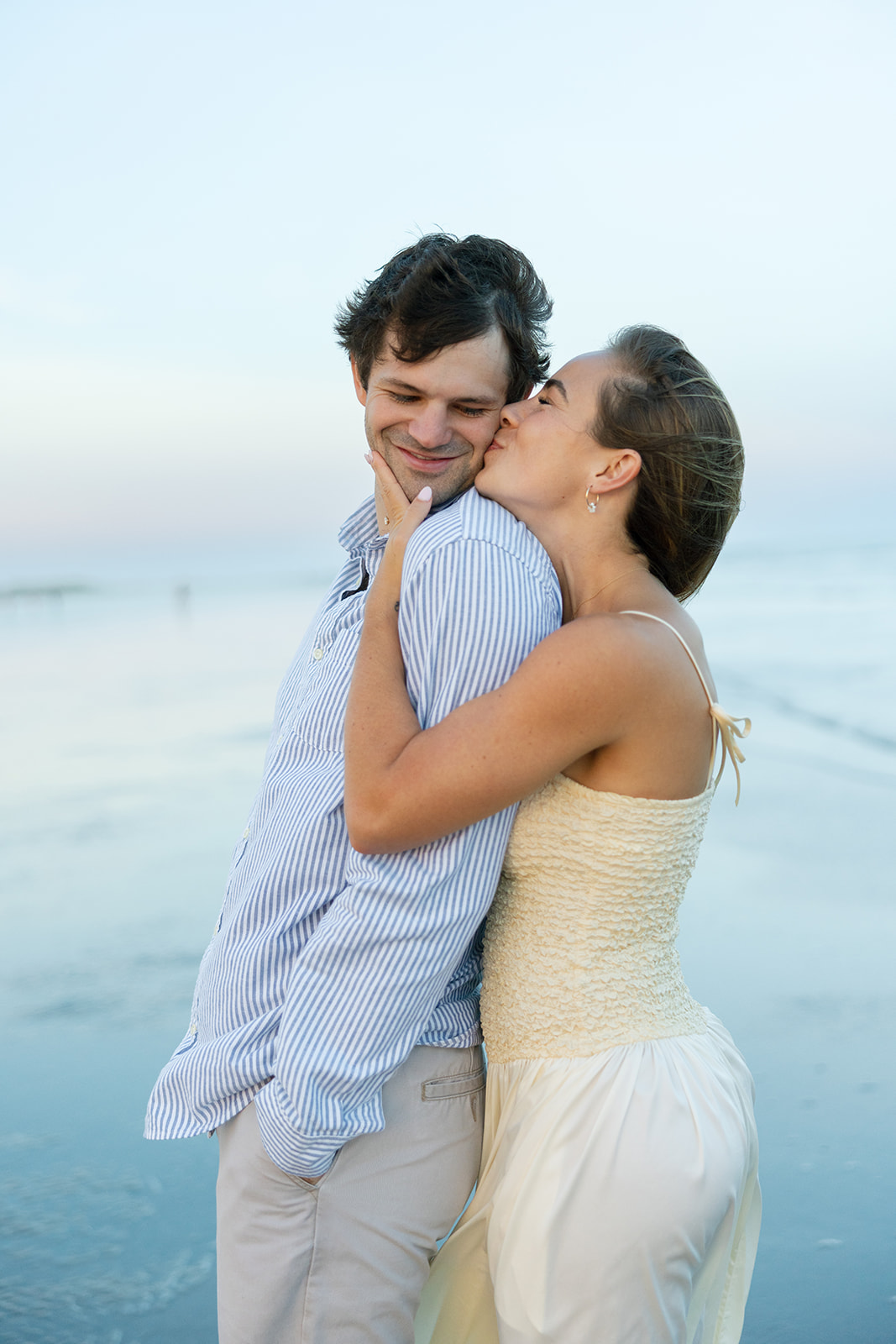 The bride-to-be kisses her fiancé on the cheek during their Charleston SC engagement photos