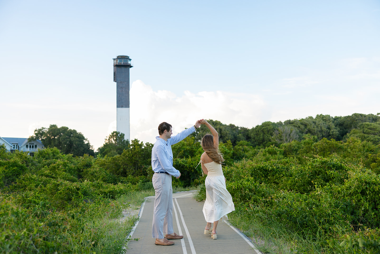 Couple dancing near Sullivan’s Island lighthouse during Charleston SC engagement session.