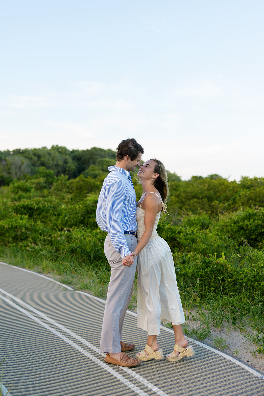Romantic moment on the boardwalk as the couple leans in, holding hands and smiling at each other during their Charleston SC engagement photos.
