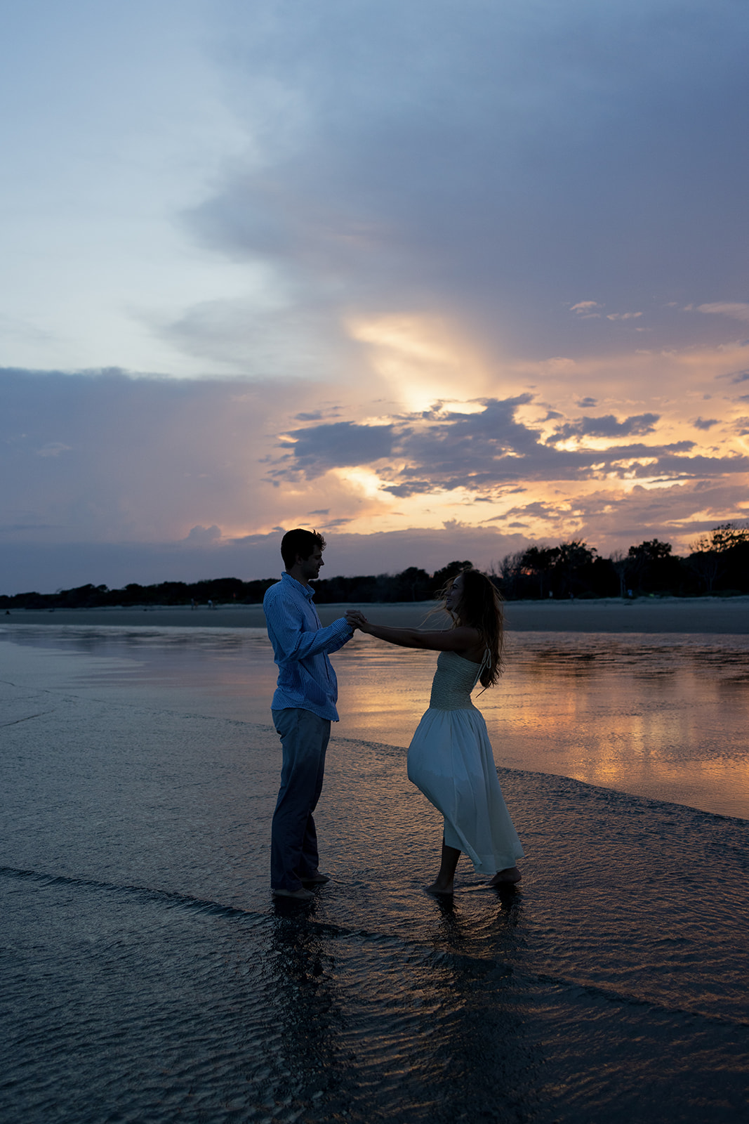 Playful moment of an engaged couple dancing in the surf at Sullivan’s Island Charleston SC, photographed during their Charleston SC engagement session.