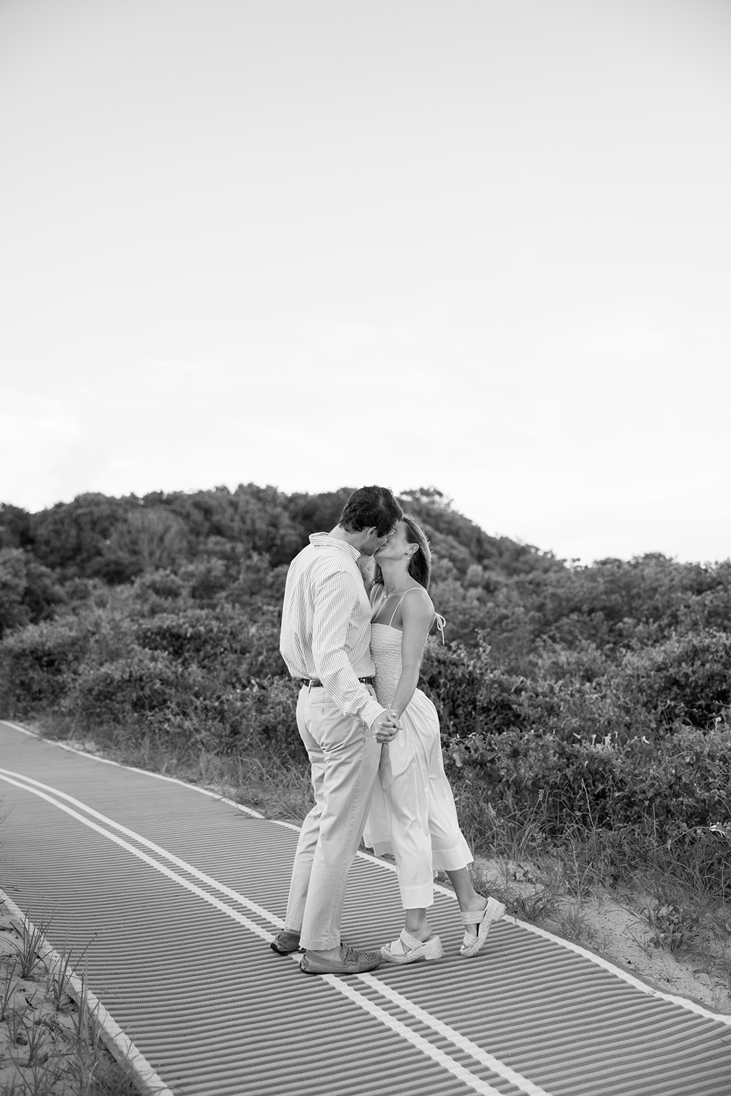 Black and white photo of the couple sharing a kiss while holding hands, a timeless Charleston SC engagement photo.