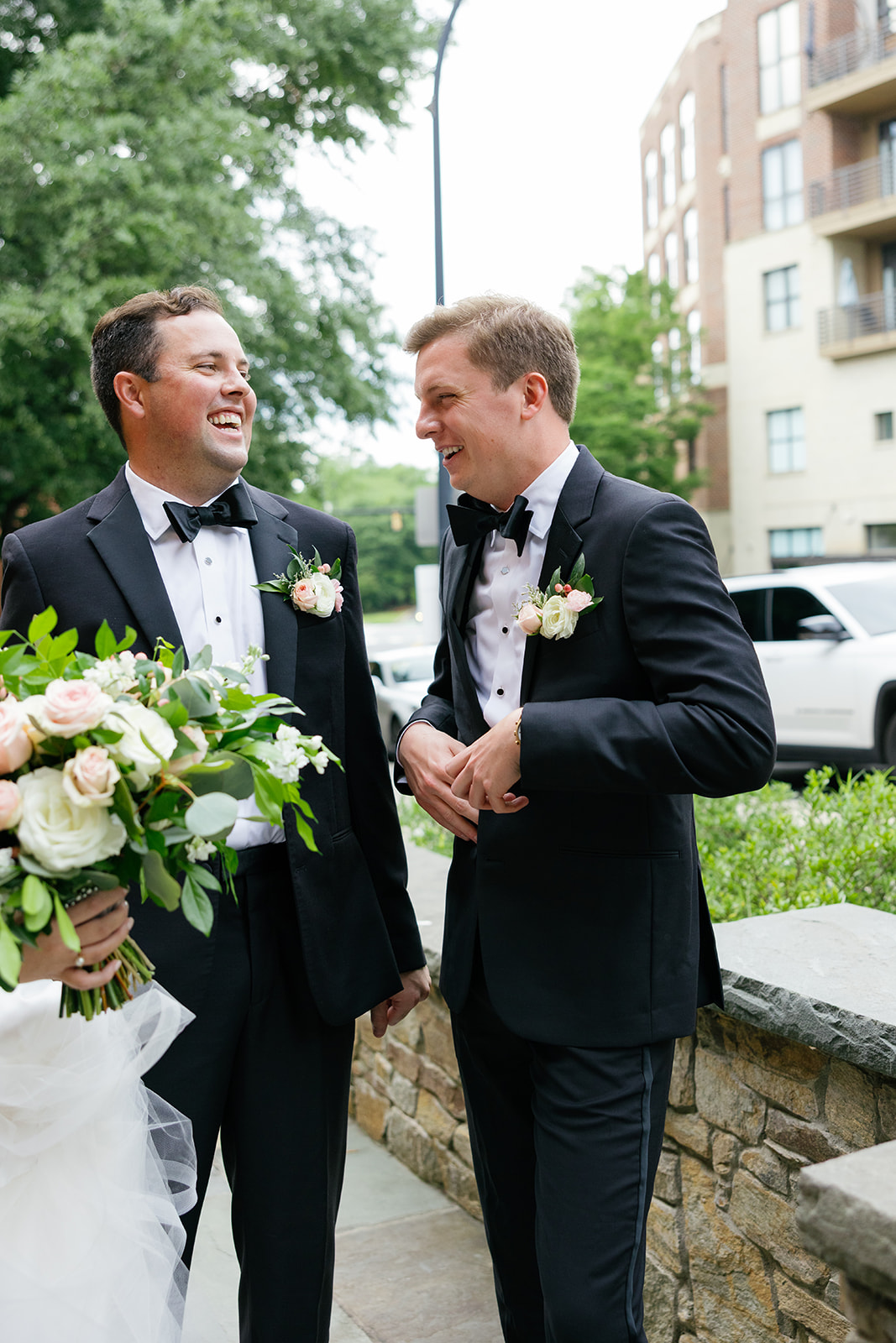 Groom and groomsman laughing together outside the venue before the ceremony.