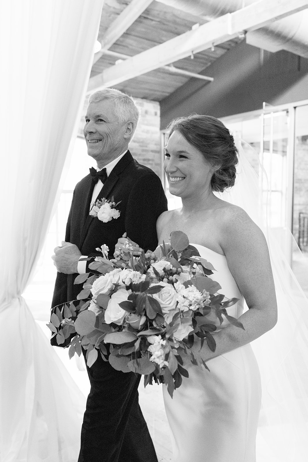 Bride and her father walking down the aisle toward the altar, surrounded by family and friends.
