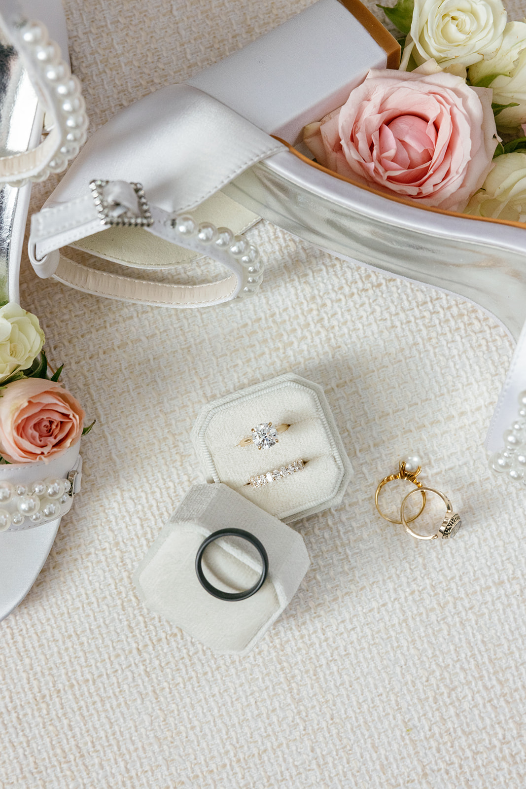 Flatlay of pearl-strap bridal shoes, pink roses, and wedding rings styled together before the Greenville SC wedding.
