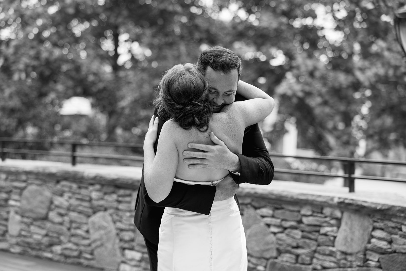 Bride and groom hugging and smiling at each other during their first look outside Huguenot Mill in Greenville, SC.
