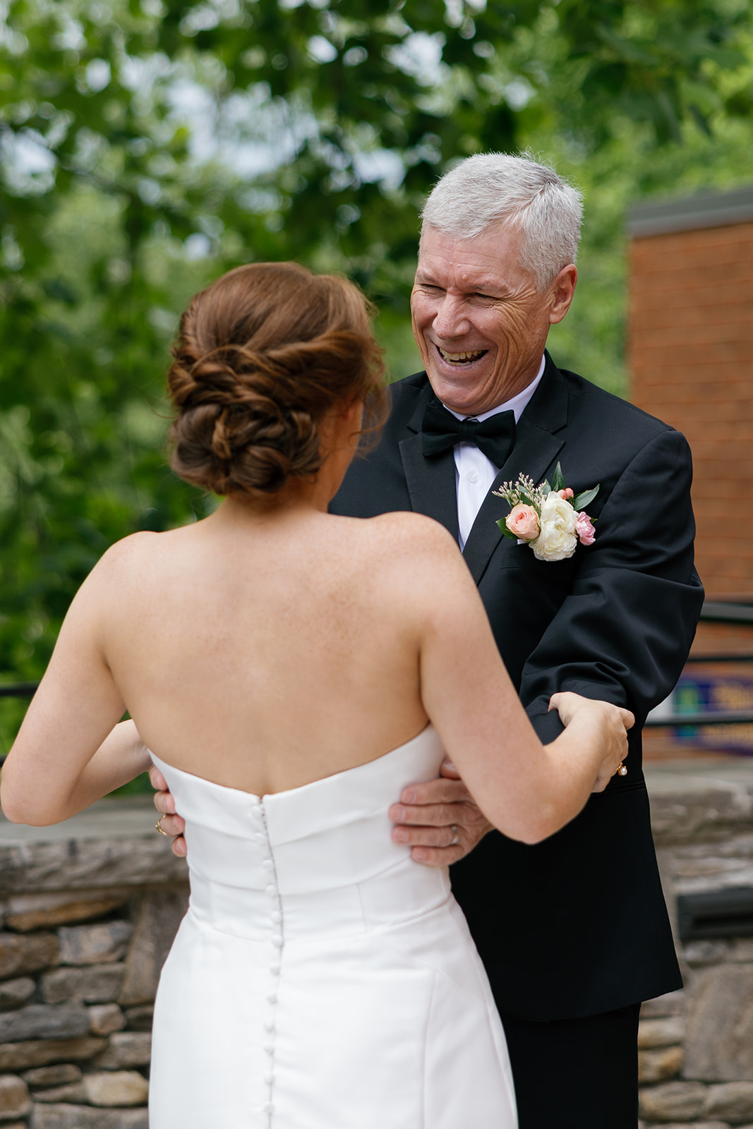 Bride and her dad smiling warmly as they hold hands during their first look outside Huguenot Loft and Mill.