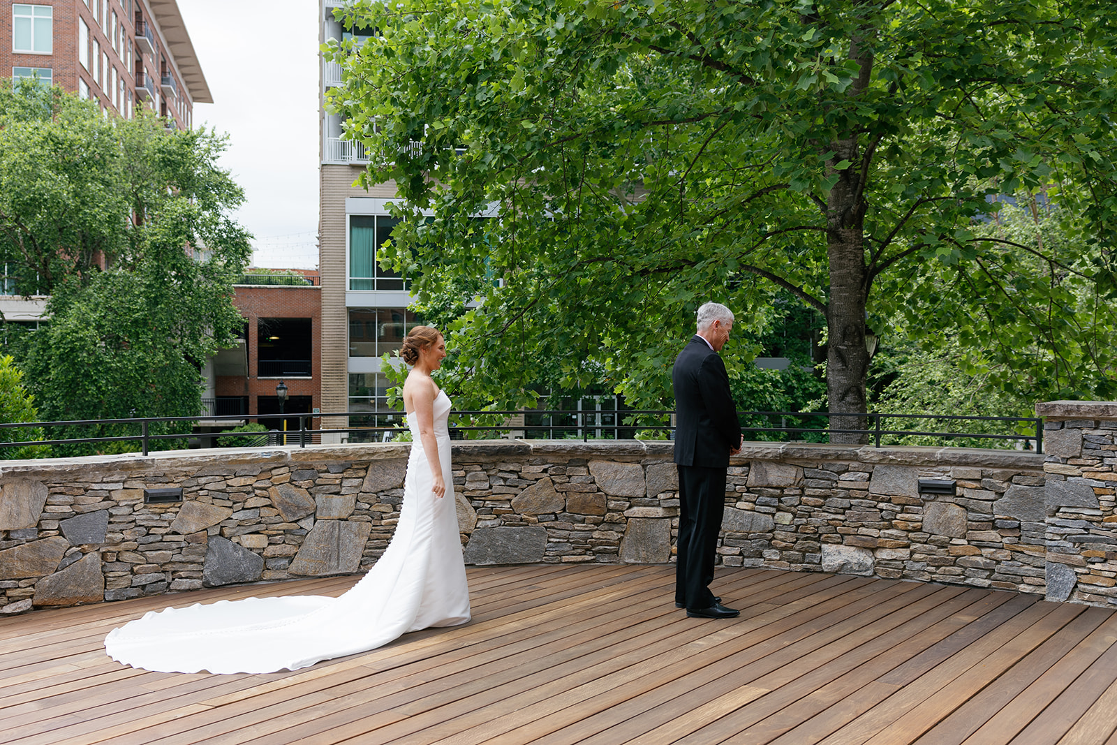 Bride walking toward her dad in a strapless gown with long train for their outdoor first look at Huguenot Loft and Mill.