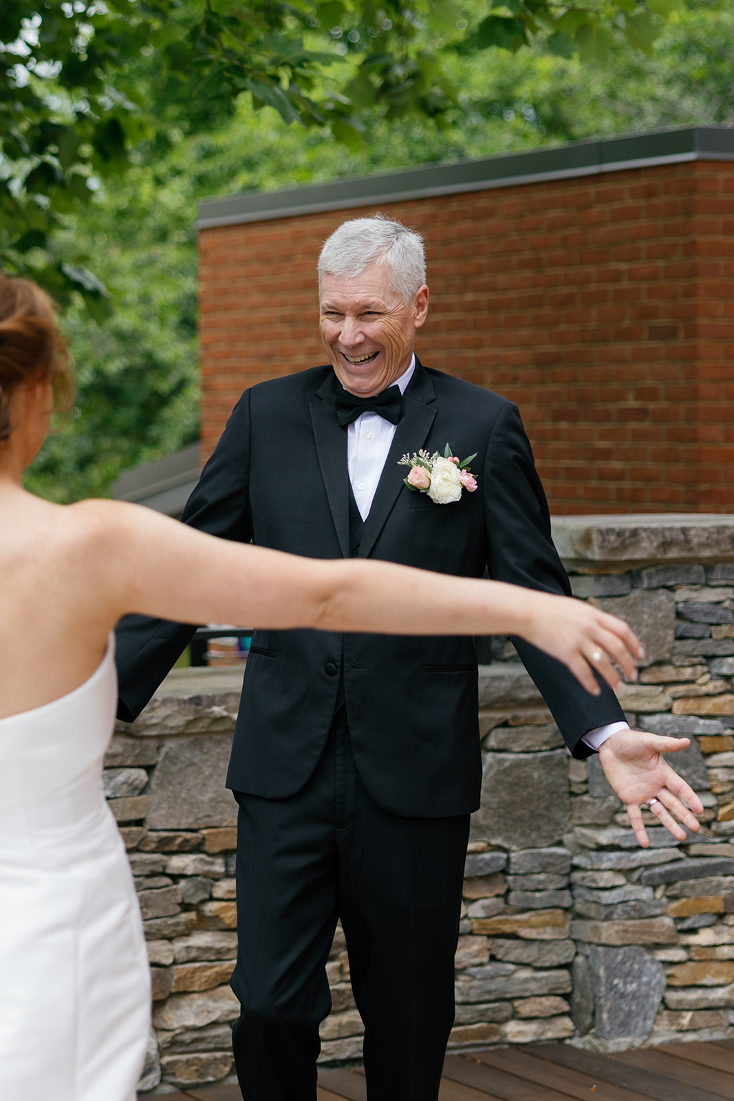 Father of the bride beaming with arms wide open during emotional first look.