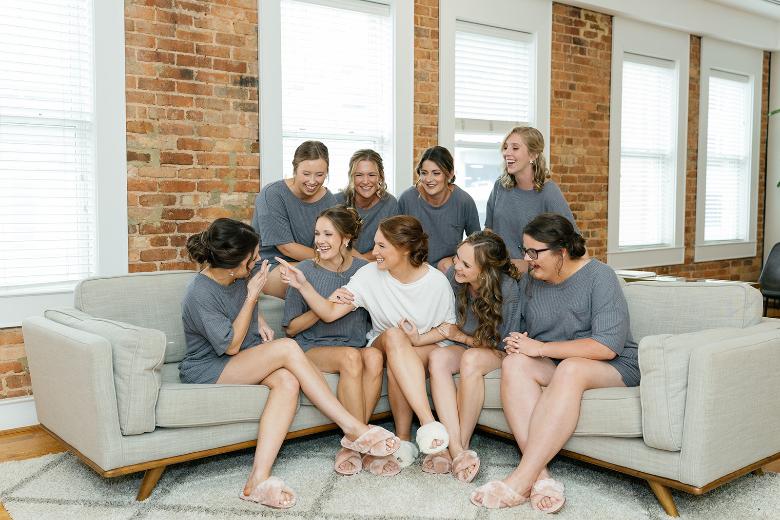 Bride laughing with bridesmaids in matching gray loungewear while getting ready at Huguenot Loft and Mill.