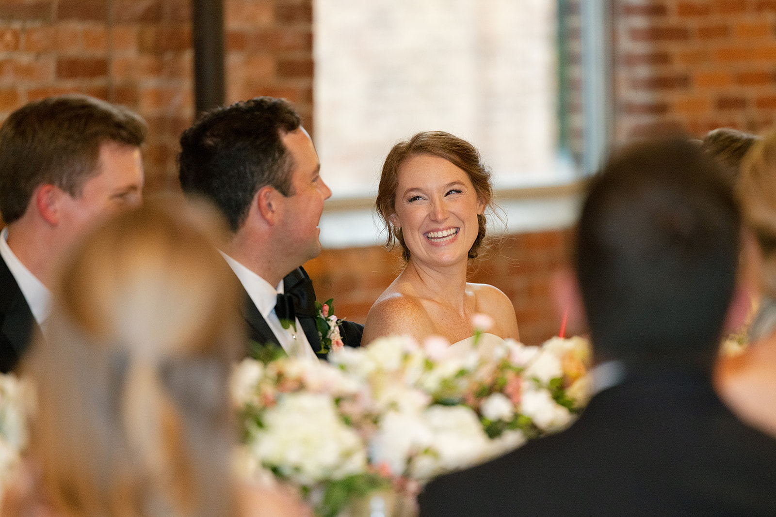 Bride laughs while looking at her groom during heartfelt toasts at their Greenville SC wedding reception.