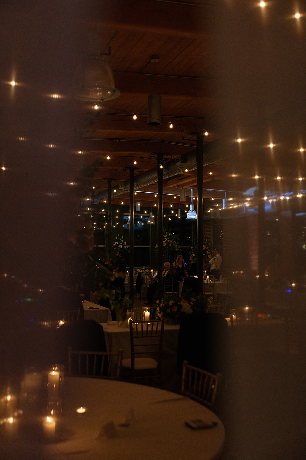 Romantic view of Huguenot Loft reception space glowing with candlelight and string lights at night in Greenville, SC.