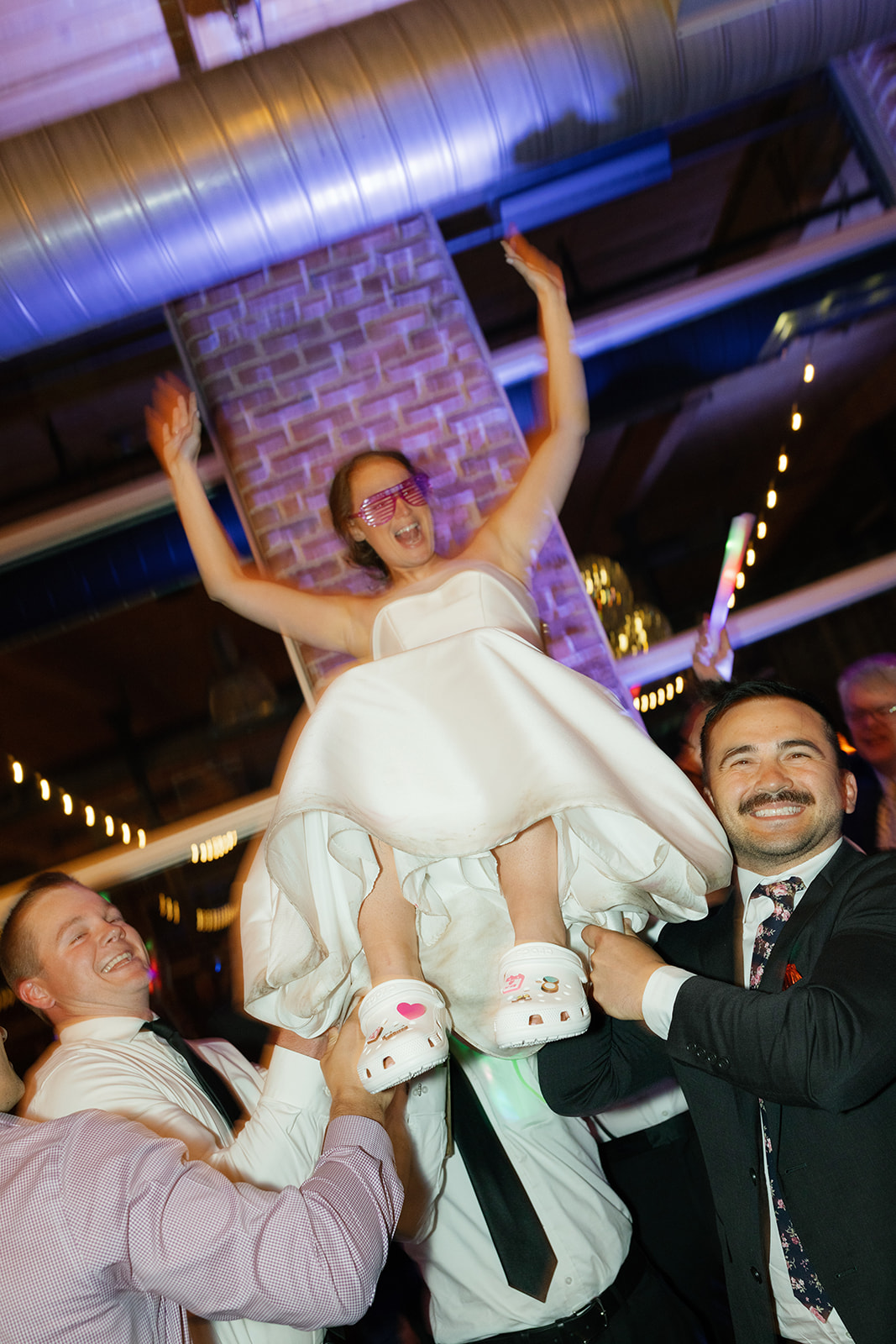 Bride lifted into the air by friends on the dance floor, laughing with arms raised during her Greenville SC wedding reception.