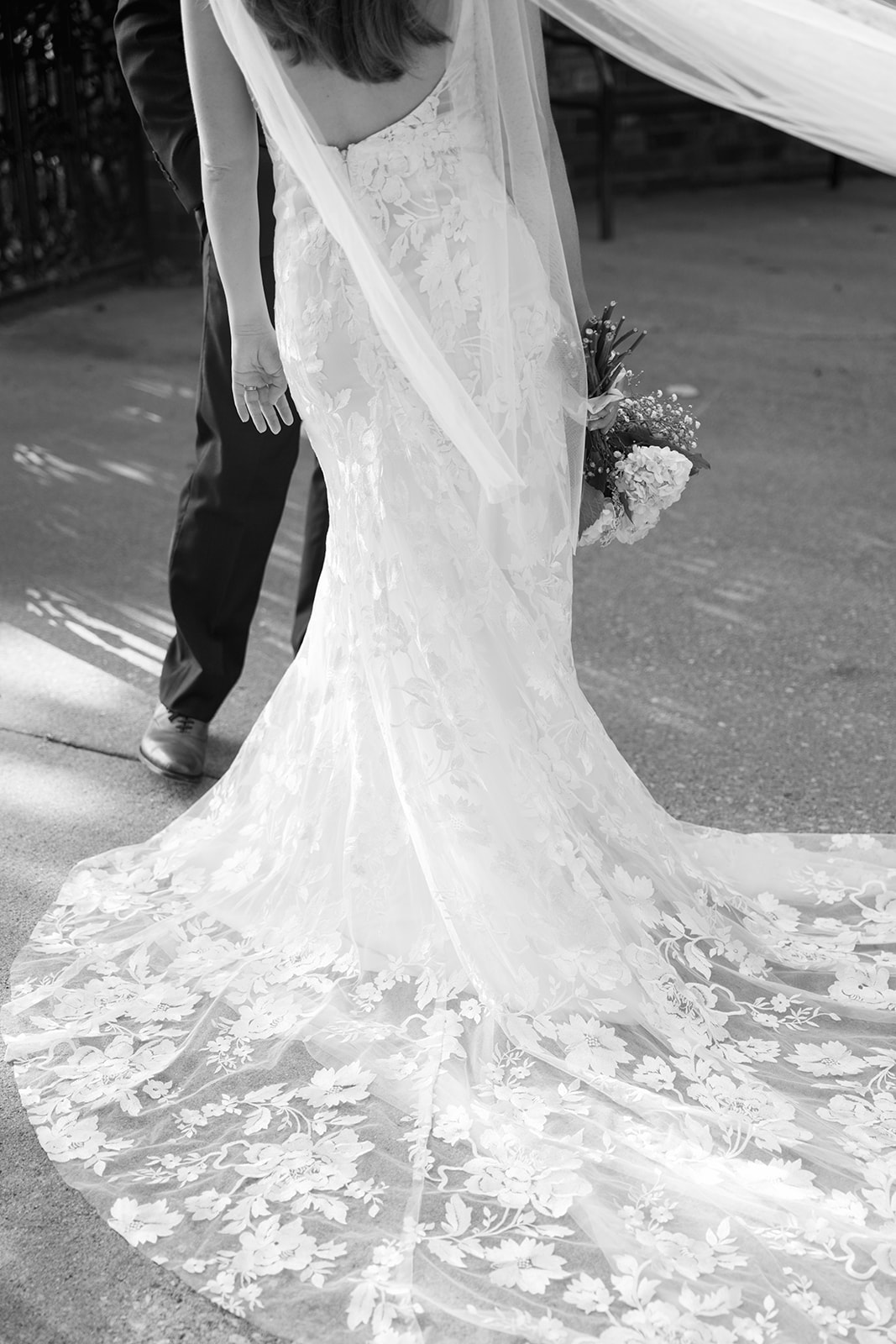 Black and white photo of bride’s lace wedding gown train flowing behind her, captured by a wedding photographer in Greenville, SC.