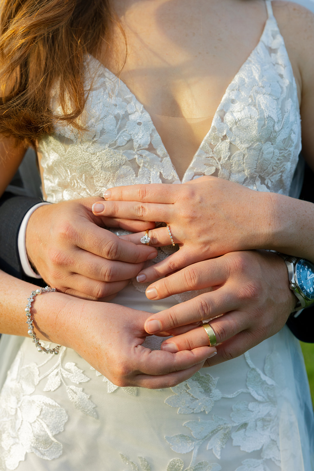 Close-up of bride and groom’s hands stacked together, showing off their wedding rings.
