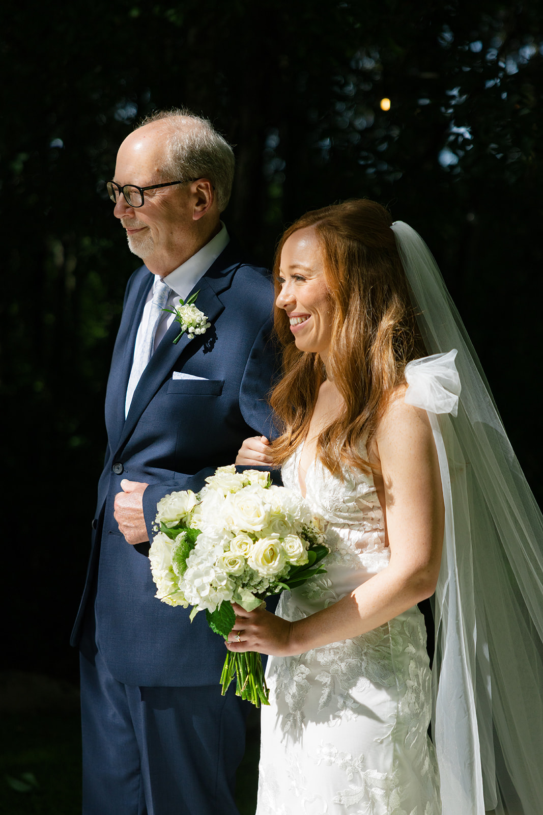 heartfelt wedding photo in Greenville, SC, with the bride carrying white roses and her father escorting her to the ceremony.