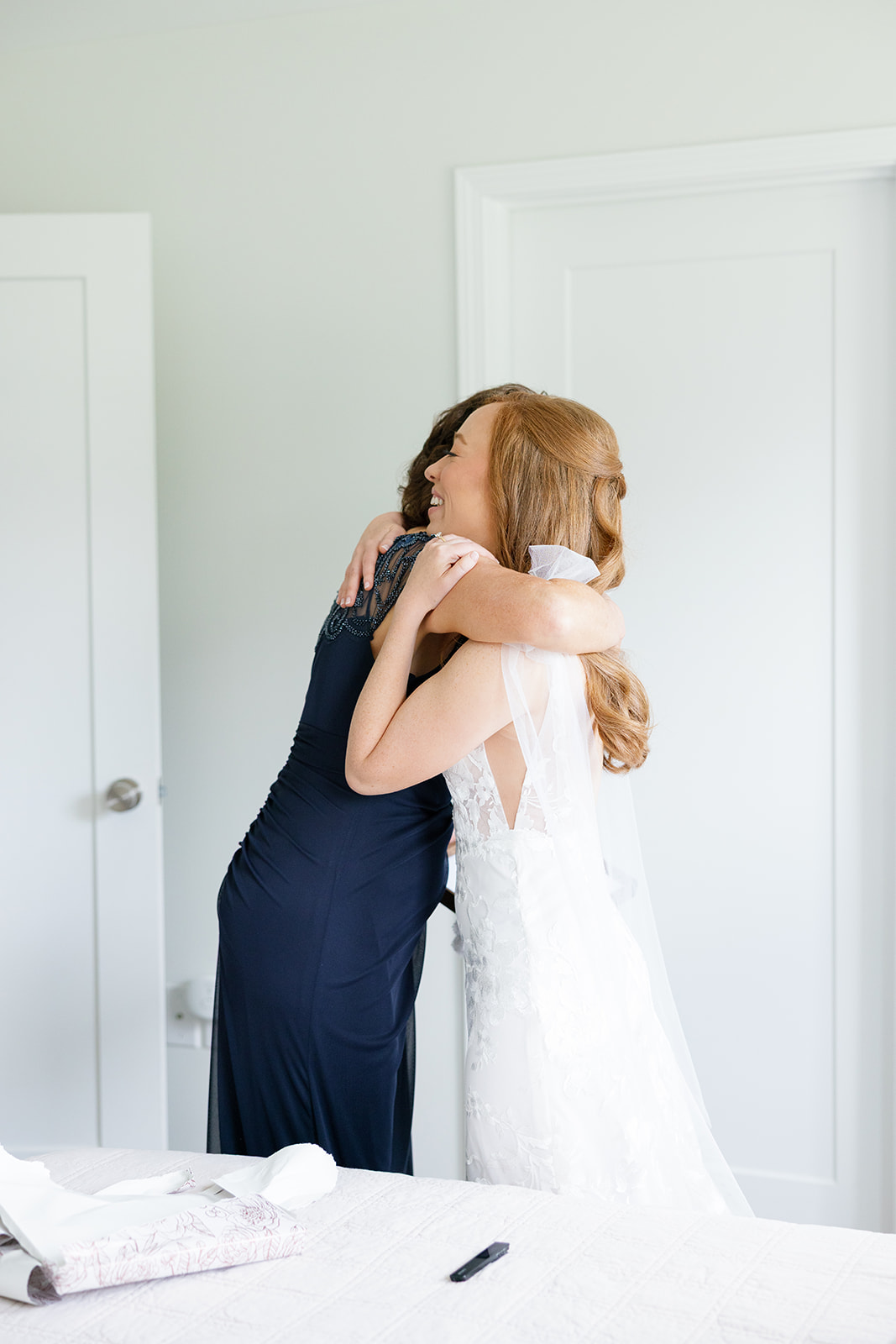The bride and her mother share a warm hug in a candid wedding photography moment before the ceremony.